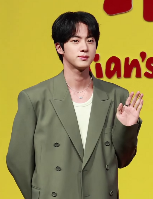 BTS’s Jin at the April 2025 press conference for “Kian’s Bizarre B&B,” wearing a tan blazer and black shirt