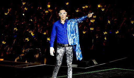 T.O.P attending an event in 2012, wearing a sharp suit and blue hair.