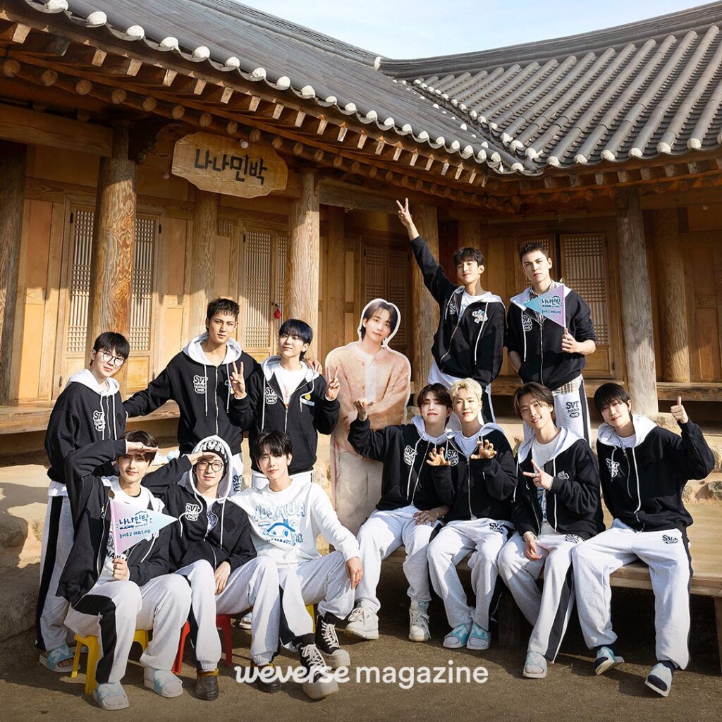 NCT DREAM members backstage holding signs after their performance, wearing blue robes and white outfits